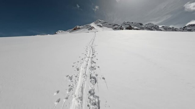 FPV sports drone shot approaching climbing skiers on snowy mountain winter summit extreme adventure. Aerial view snow trace people hiking cliff ridge alpine sunny landscape mountaineering alpinism 4k