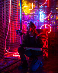 Caucasian woman with a gas mask in her hands in a neon studio. 