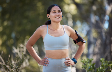 Woman, earphones and fitness arm band in nature park break, garden or sustainability environment for exercise, training or workout. Smile, happy or resting runner listening to music or health podcast