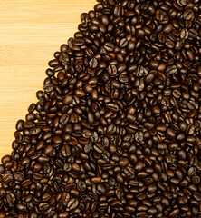 The whole coffee beans are photographed in the upper corner and placed on a wood grain table before being ground for a drink.