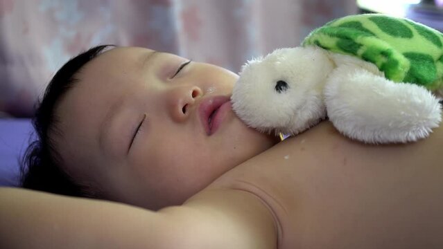 Baby boy sleep with his plush toy turtle at bed