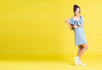portrait of Asian woman in skirt posing on yellow background