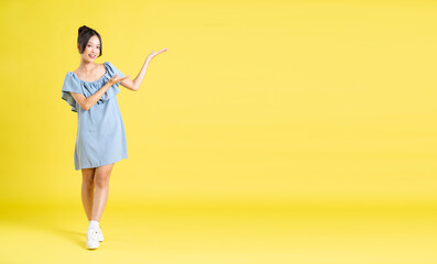 portrait of Asian woman in skirt posing on yellow background