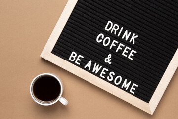 Top view of cup of black coffee and phrase drink coffee and be awesome on letter board.
