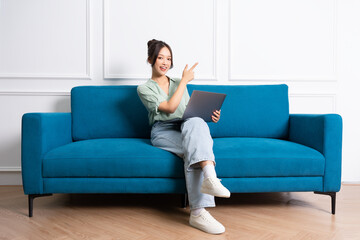 Fototapeta premium image of young Asian girl sitting on sofa at home
