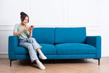Naklejka na ściany i meble image of young Asian girl sitting on sofa at home
