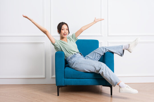image of young Asian girl sitting on sofa at home