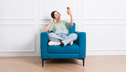 image of young Asian girl sitting on sofa at home