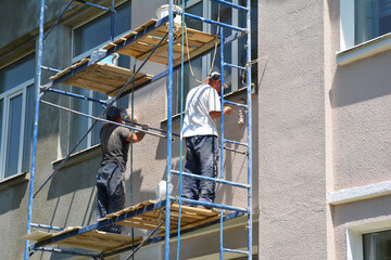 Builder contractors painting external walls outside house facade. Close up on painting house...