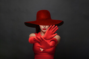 Stop gesture. Brunette woman hands in red silky gloves and wide broad brim hat showing stop...