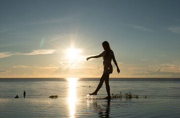 Asia woman walking alone the sea view infinity pool in sunrise, morning time