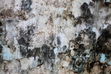 A weathered concrete wall with cracks and peeling paint, showing signs of age and decay.