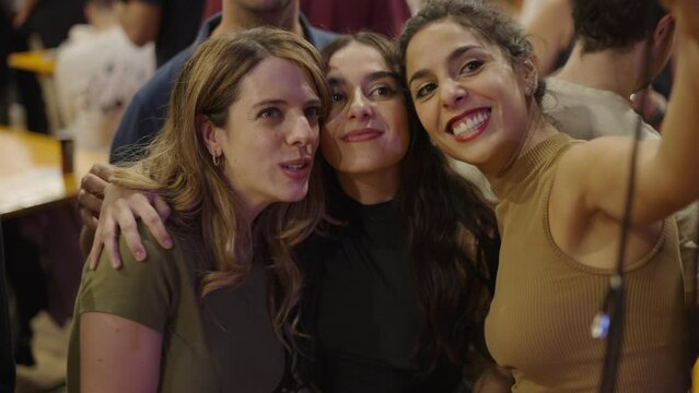 Three spanish girls taking a picture with a smartphone while smiling 