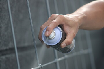 Closeup of man painting a fence with spray paint or aerosol paint