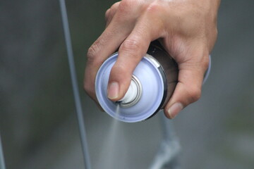 Closeup of man painting a fence with spray paint or aerosol paint
