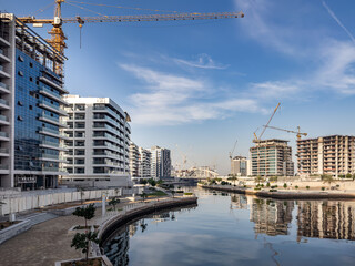 Residential apartment buildings under construction along the waterfront promenade in Al Raha Beach,...