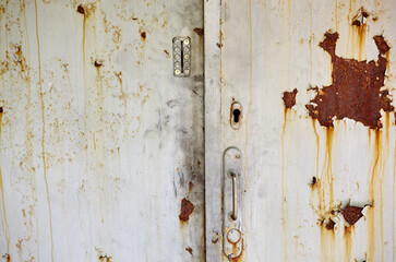 The old door to the building. Painted metal door with rust spots and scratches, entrance to the...