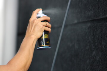 Closeup of man painting a fence with spray paint or aerosol paint