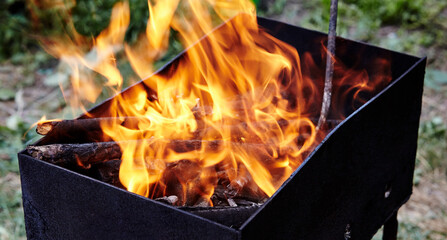 Burning red hot sparks fly from fire. Barbecue gril with glowing and flaming hot charcoal and firewood