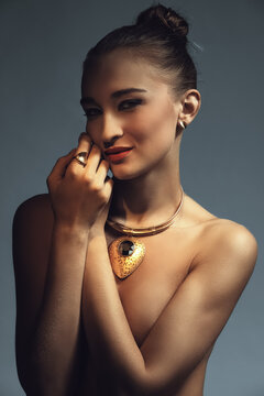 Dark and moody photo of a model with large golden necklace
