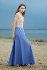 Fototapeta na wymiar Dreamy woman in long blue skirt and lace blouse on the beach