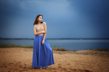Fototapeta na wymiar Calm lonely fashion model standing on a beach in a cloudy day.