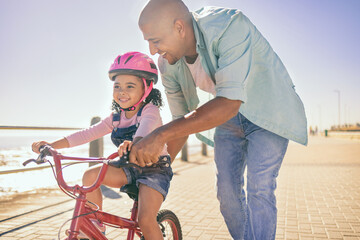 Black girl, bike and learning with dad, smile and park in sunshine, safety or happiness by sea....