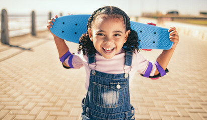 Child, skateboard and excited for fun activity outdoor on promenade with smile, happiness and energy on summer vacation. Portrait of black girl with safety gear for elbow for skating or skateboarding © Alexis S/peopleimages.com