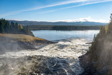 Famous waterfall Tannforsen northern Sweden, with a rainbow in the mist and rapid flowing cascades of water