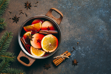 Hot Mulled wine cooking at home for happy christmas time. Red wine, orange, apple and spices -...