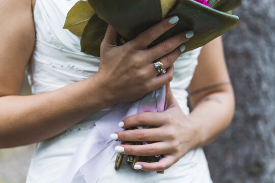 Unrecognizable Turkish bride in sleeveless wedding dress holding her bridal bouquet with both hands, showing her new wedding ring and beautiful nails. High quality photo