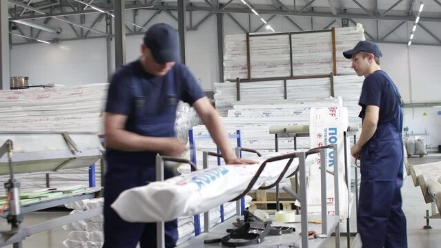 Workers in a factory carry out technological processes on a conveyor line in protective overalls