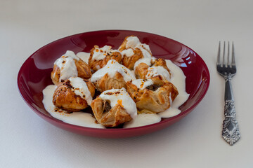 Ravioli made with puff pastry with yoghurt and tomato sauce on the plate; Turkish name (Sosyete ravioli)