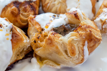 Ravioli made with puff pastry with yoghurt and tomato sauce on the plate; Turkish name (Sosyete ravioli)