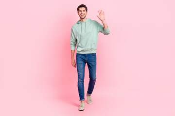 Full length photo of satisfied man dressed grey denim clothes raise arm say hi rejoice meet close friend isolated on pink color background © deagreez