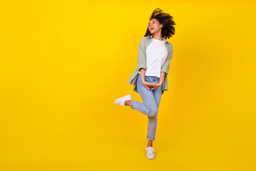 Full body photo of pretty young woman wavy hair dance good mood empty space dressed stylish khaki look isolated on yellow color background