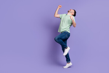 Full length photo of overjoyed ecstatic champion guy with brunet hairdo dressed t-shirt raise fists up isolated on purple color background