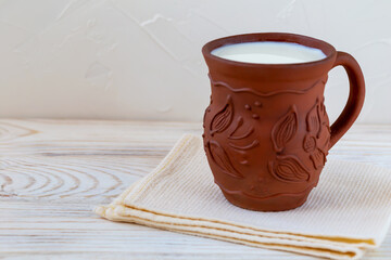 Fresh milk in a clay jug on a towel close-up