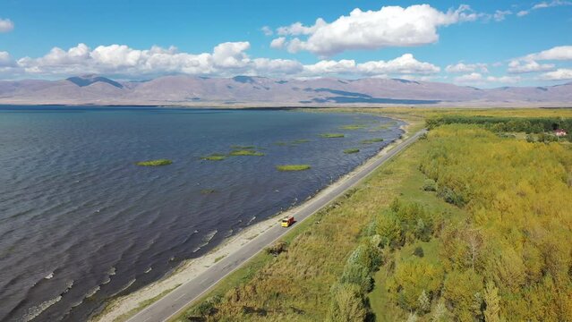  Aerial footage road between lake and field. Road near Sevan lake in Armenia, Caucasus. Highway traffic near water.   Most popular lake in Armenia, western Asia.