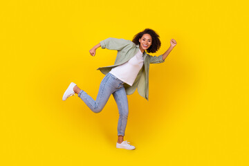 Fototapeta na wymiar Full body photo of funny young woman curly hair running fast hobby free time wear trendy khaki outfit isolated on yellow color background