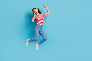 Fototapeta na wymiar Full length photo of cheerful cool lady earbuds listen favorite singer melody quality sound empty space isolated on blue color background