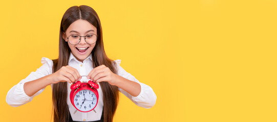 amazed child in school uniform and glasses with alarm clock showing time, school time. Teenager child with clock alarm, horizontal poster. Banner header, copy space.