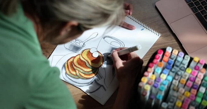 Woman draws drawing of food cup and pancakes