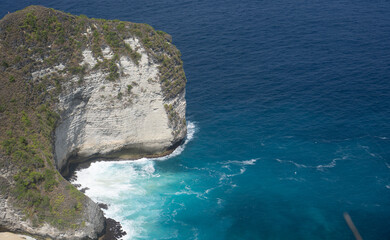 Blue water and rock cliffside at kelingking beach, nusa penida. The sunny weather provides beautiful lightning for the scenery.