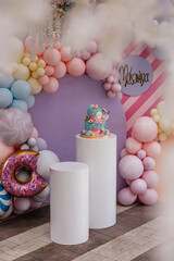 Bright colored handmade cake with decorative elements for a children's party on the background of a pink wall with balloons