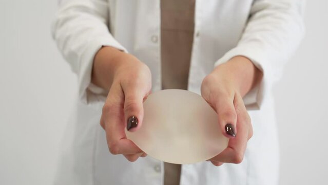 Plastic surgeon demonstrating the resistance of the breast prosthesis by stretching and squeezing it.
