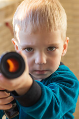 Toddler looking at the camera with a serious angry face and aiming with a child's pump gun