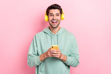 Portrait of carefree overjoyed person hold telephone toothy smile enjoy song isolated on pink color background