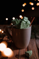 Hot beverage with cinnamon and Christmas marshmallows in  Cup on dark festive background. Xmas drink. Mug with hot chocolate and marshmallow on wooden table