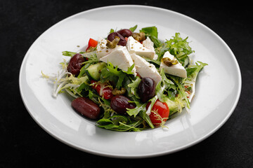 Greek salad on a plate, on a dark background